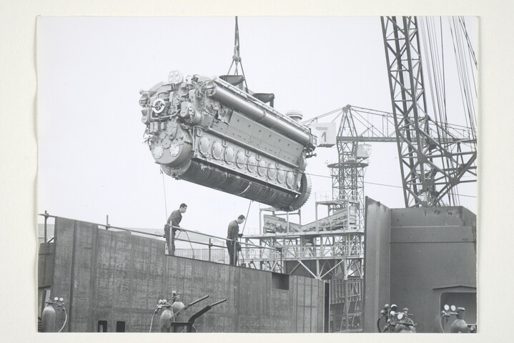 S.5219(12)0460; Foto's van de plaatsing van de 2360 PK M.A.N. dieselmotor met behulp van een drijvende bok in het vrachtschip ms. 'Amstelstroom' [...]; fotoreportage