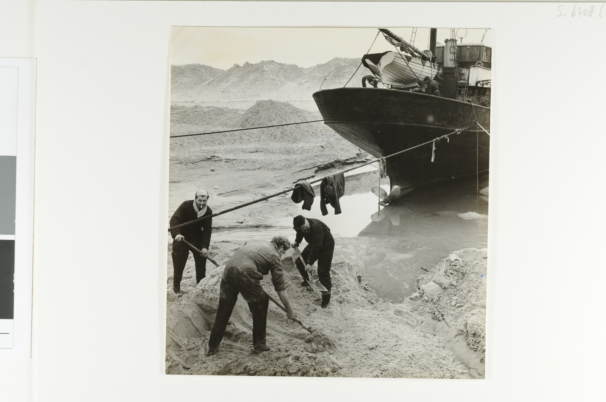 S.6408(1077); Bergers graven met de hand een geul voordat de Helderse viskotter 'De drie Gebroeders' (HD 79) vlot wordt getrokken van het strand van Texel [...]; foto