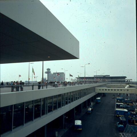 S.9100(2705); Dia van een wandelpier met het hoofdkantoor van de KLM op de achtergrond; diapositief