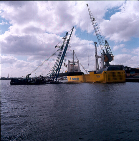 S.9100(6899); Dia van het zwaarladingschip 'Happy Rider' ladende met twee bokken een offshore ponton; diapositief