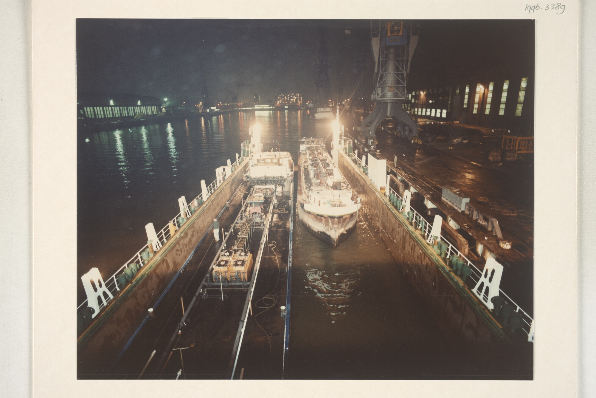 1996.3389; Avondopnames van het klaarmaken voor transport met een dokschip van de binnenvaarttankers ms. 'Leonidas VII' van Leonidas Tankvaart BV; fotoreportage