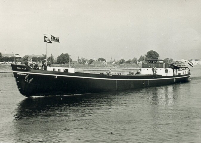 S.5219(12)0705; Foto's van het vrachtschip ms. Roekwijk van de Nieuwe Rijnvaart Maatschappij op een rivier en aan een kade; fotoreportage