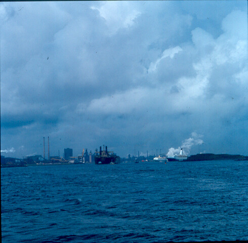 S.9100(8860); Dia met kijkje op hoogovens vanaf Zuidpier met op voorgrond o.a. de 'Torne'; diapositief