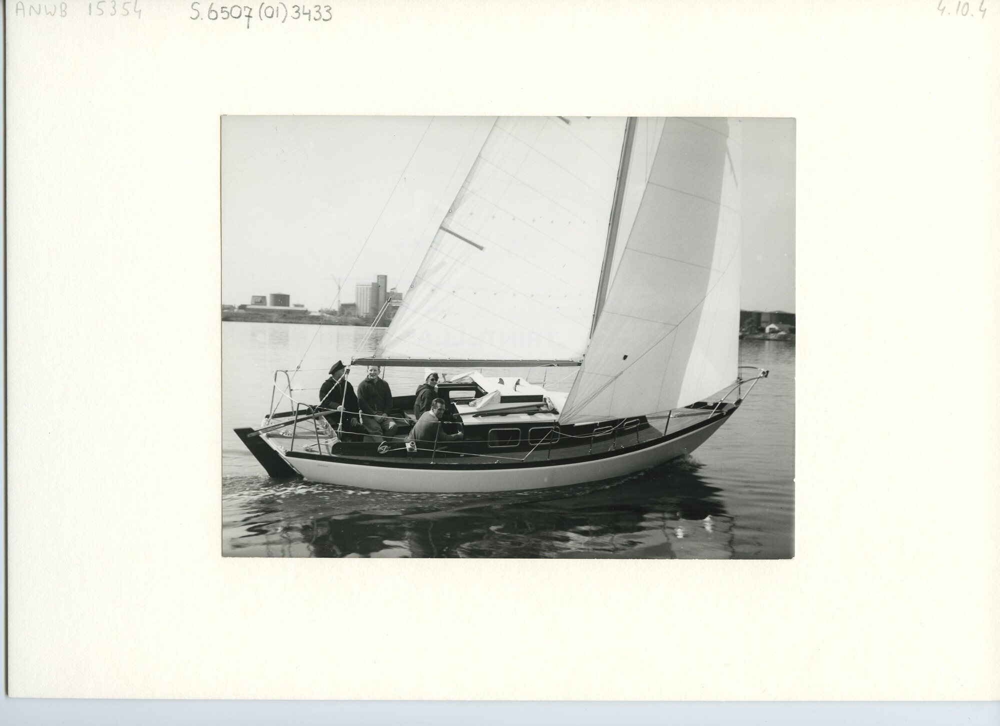 S.6507(01)3433; Foto van een wit polyester zeegaand kajuitzeiljacht type Trintella met aangehangen roer en helmstok, donker dek en opbouw; foto