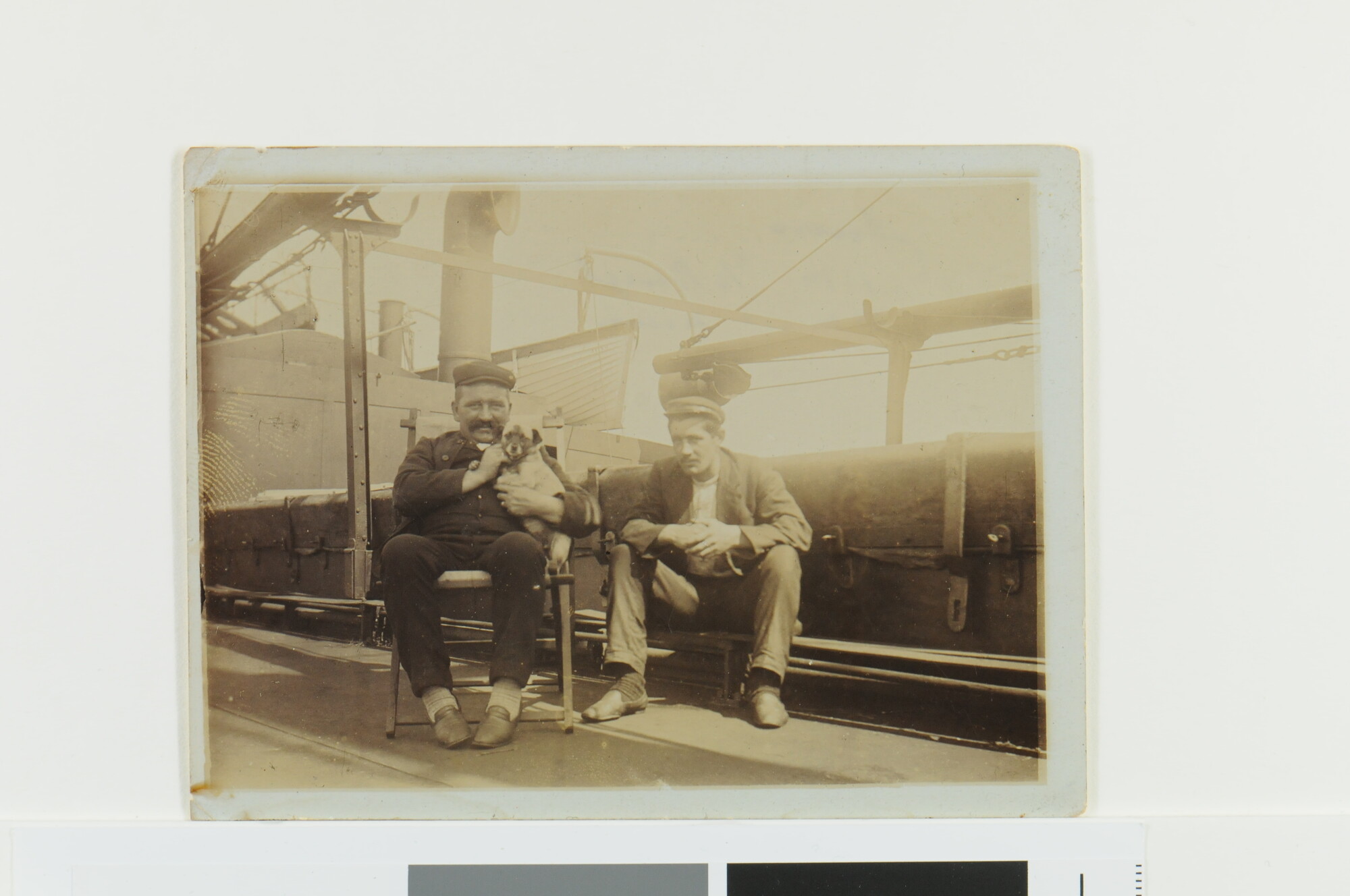 S.5638(13)2; De eerste machinist v.d. Burgh en de tweede machinst Van Duin (met scheepshond) op het dek van vrachtschip ss. Juno van de KNSM; foto