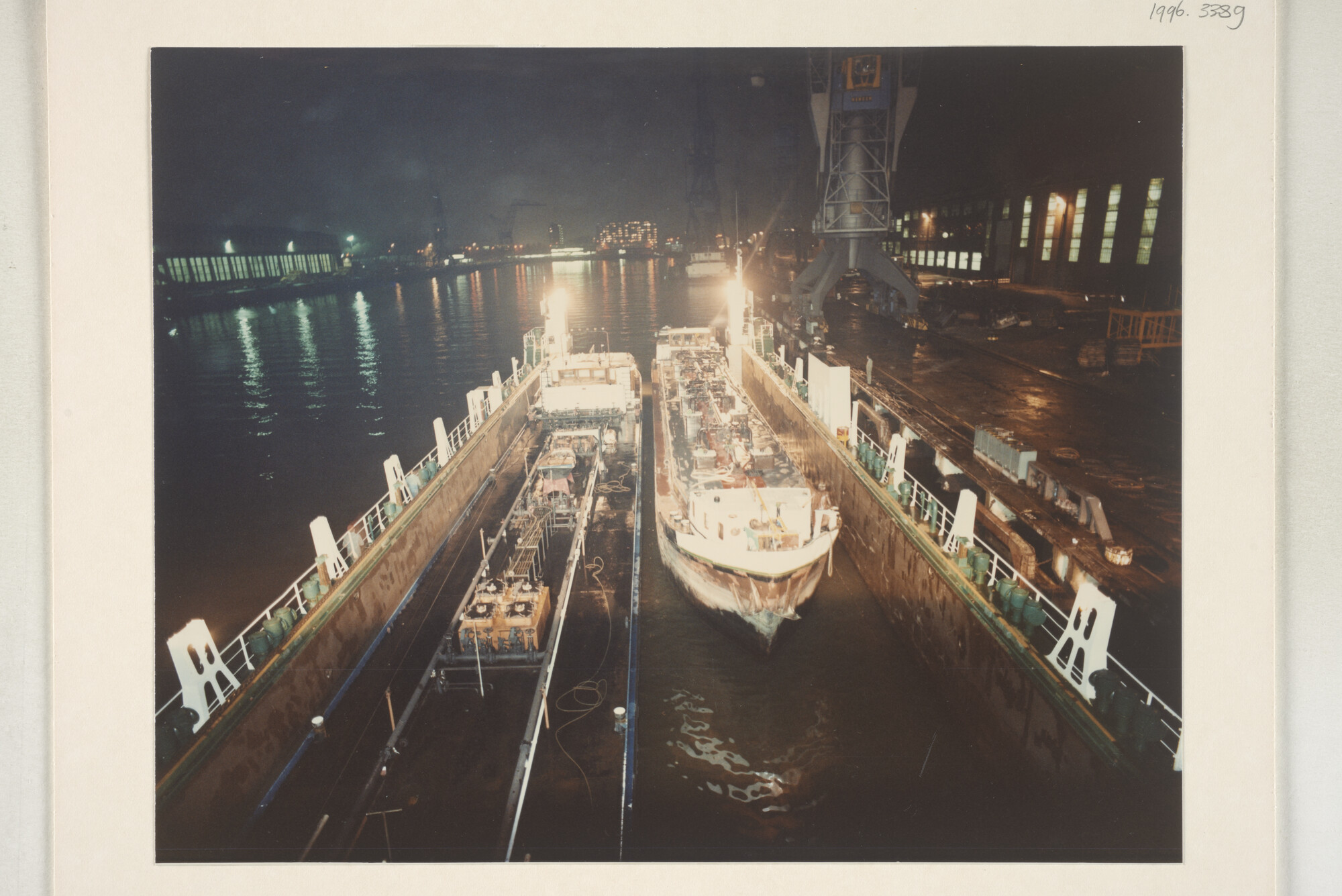 1996.3389; Avondopnames van het klaarmaken voor transport met een dokschip van de binnenvaarttankers ms. 'Leonidas VII' van Leonidas Tankvaart BV; fotoreportage