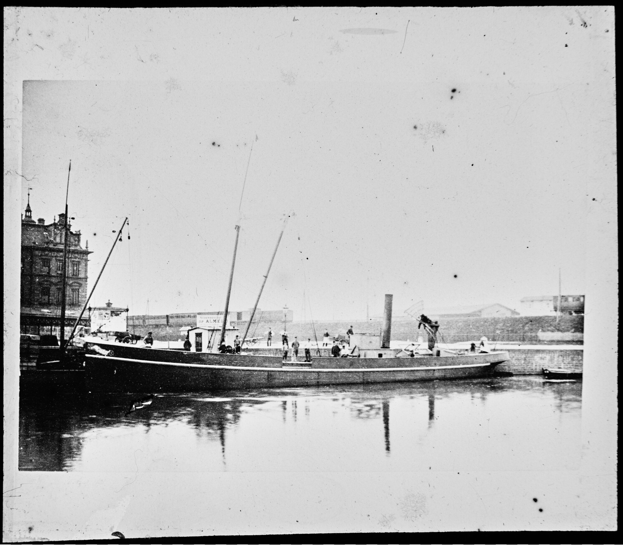 S.1156(06)026; Zijaanzicht van het vrachtschip ss. 'Almelo I' afgemeerd aan de steiger van de Stoombootreederij op Almelo bij de Droogbak in Amsterdam, 1891; lantaarnplaatje