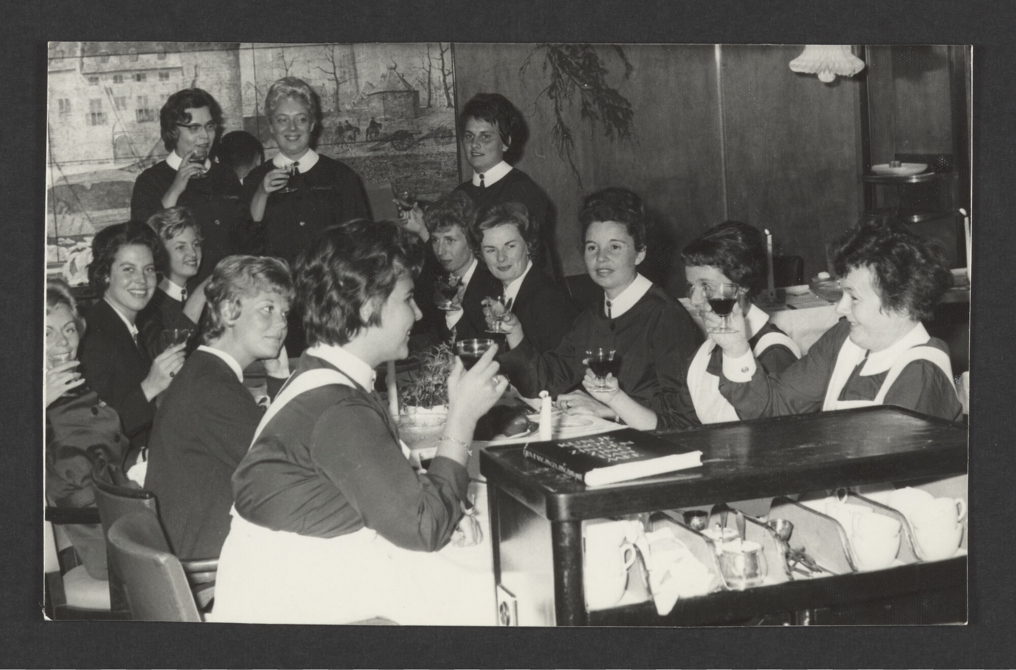 2023.0434; Zwart-wit foto van assistent purser Freddie Knol met twaalf collega's van ms. Oranje aan het kerstdiner, 1963; foto