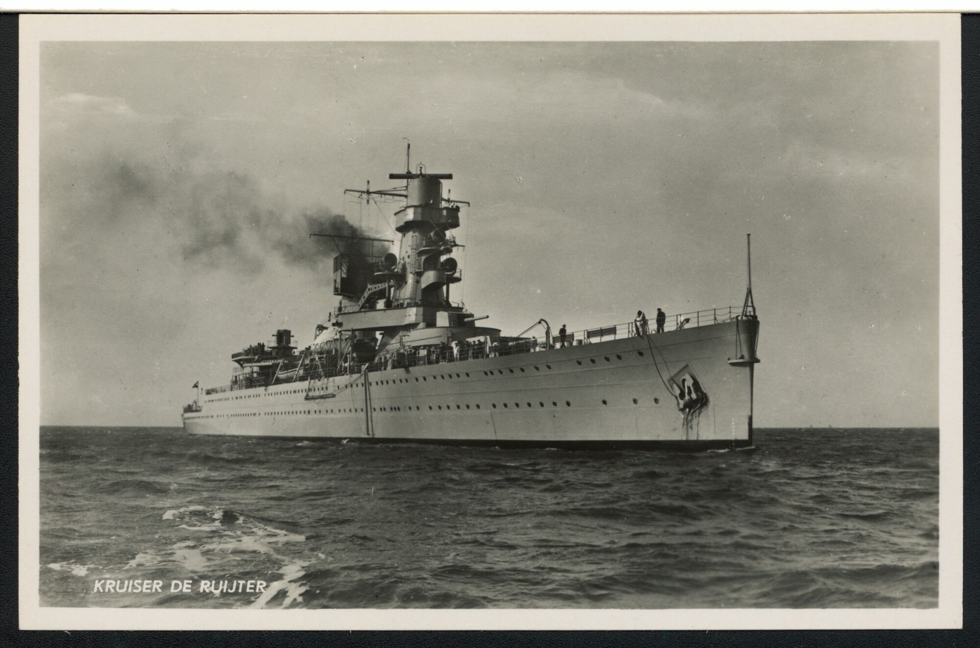 S.4380(04)284; De kruiser Hr.Ms. 'De Ruyter' van schuin voor gezien op zee; prentbriefkaart