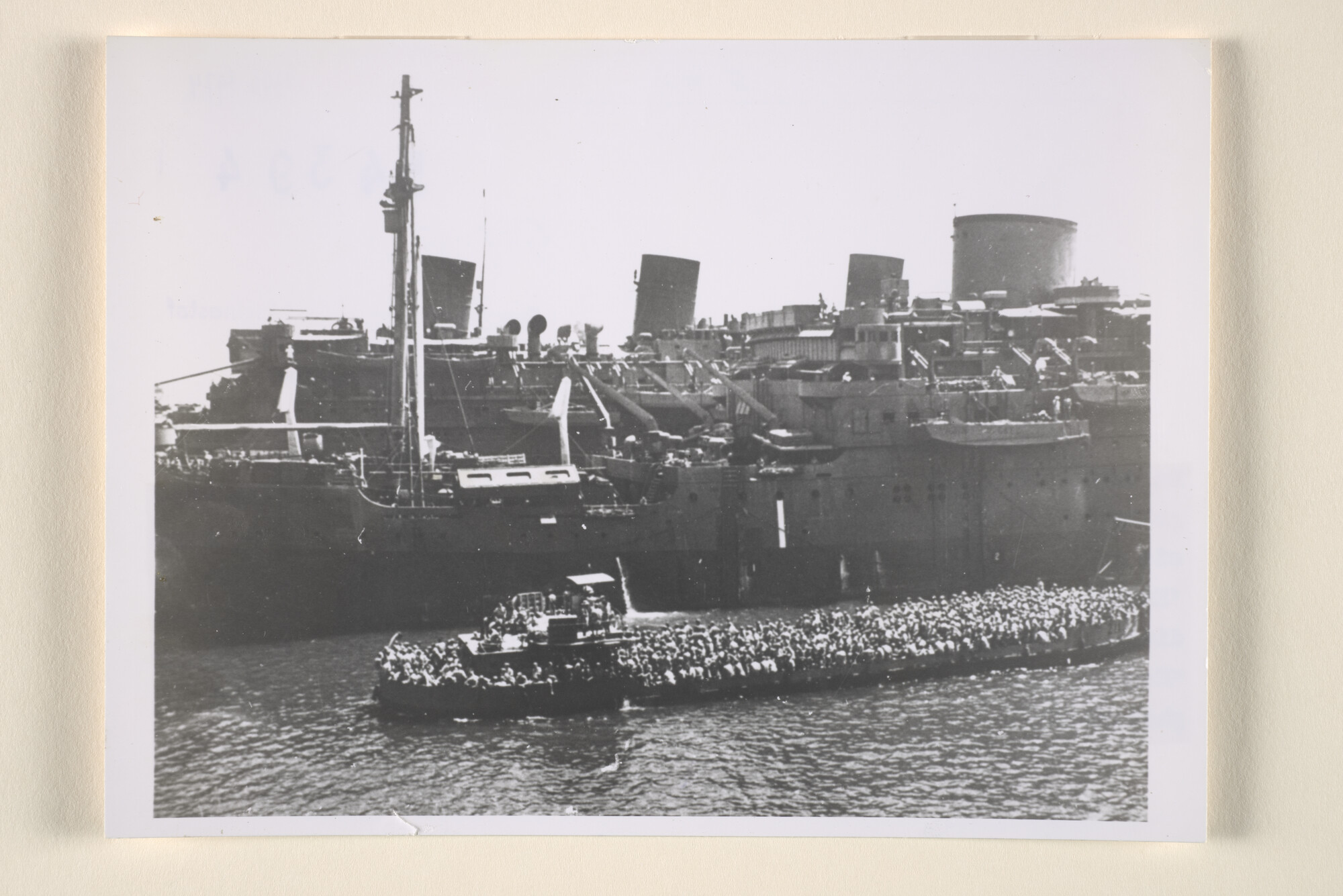 1996.3974; Een Britse LST vol met manschappen komt langszij het tot troepentransportschip omgebouwde ms. 'Tegelberg' van de KPM bij Port Said, 1943; foto