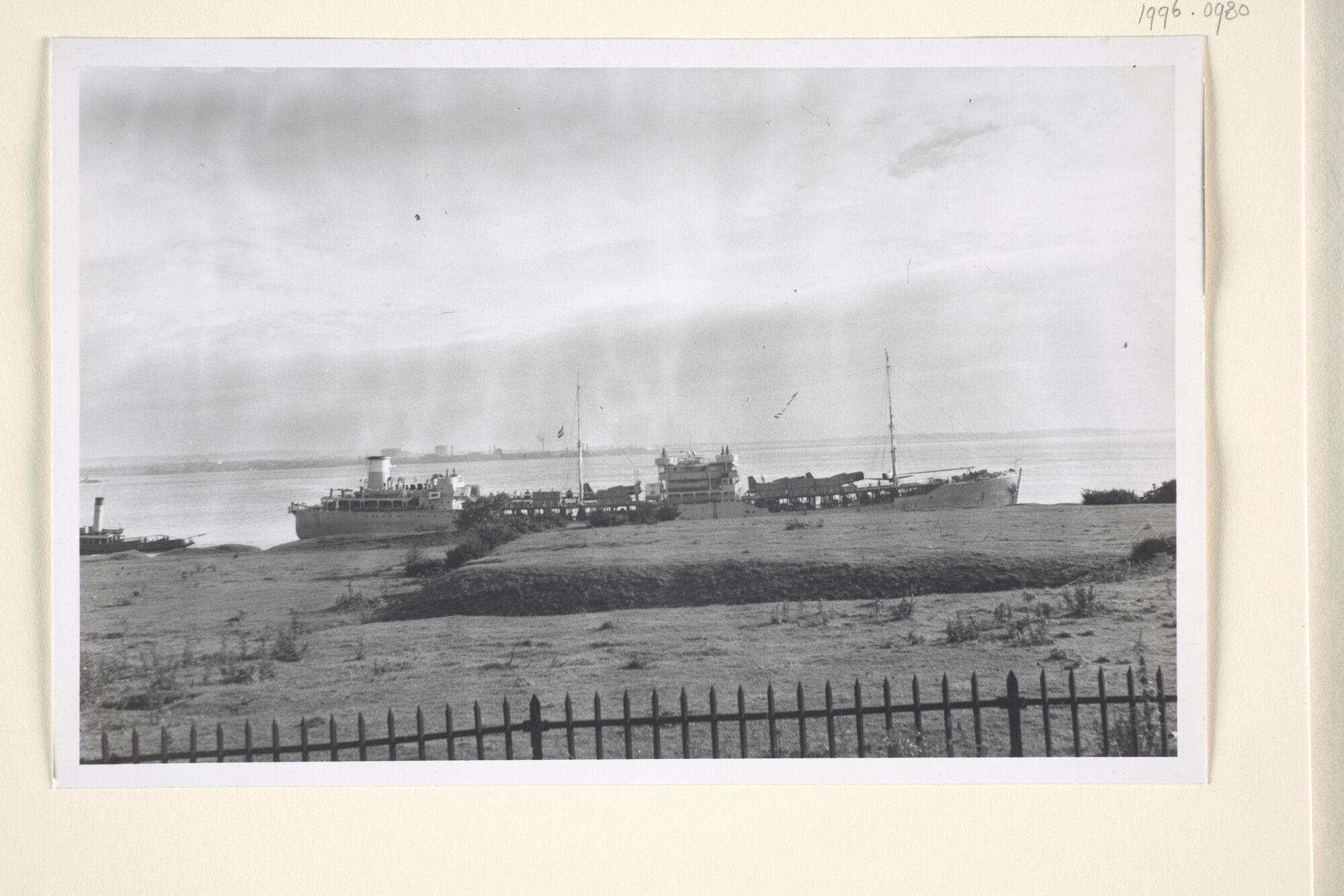 1996.0980; De tanker ms. 'Ondina', geschilderd in oorlogsgrijs en met op dek geladen vliegtuigen, wordt door twee sleepboten gesleept; foto