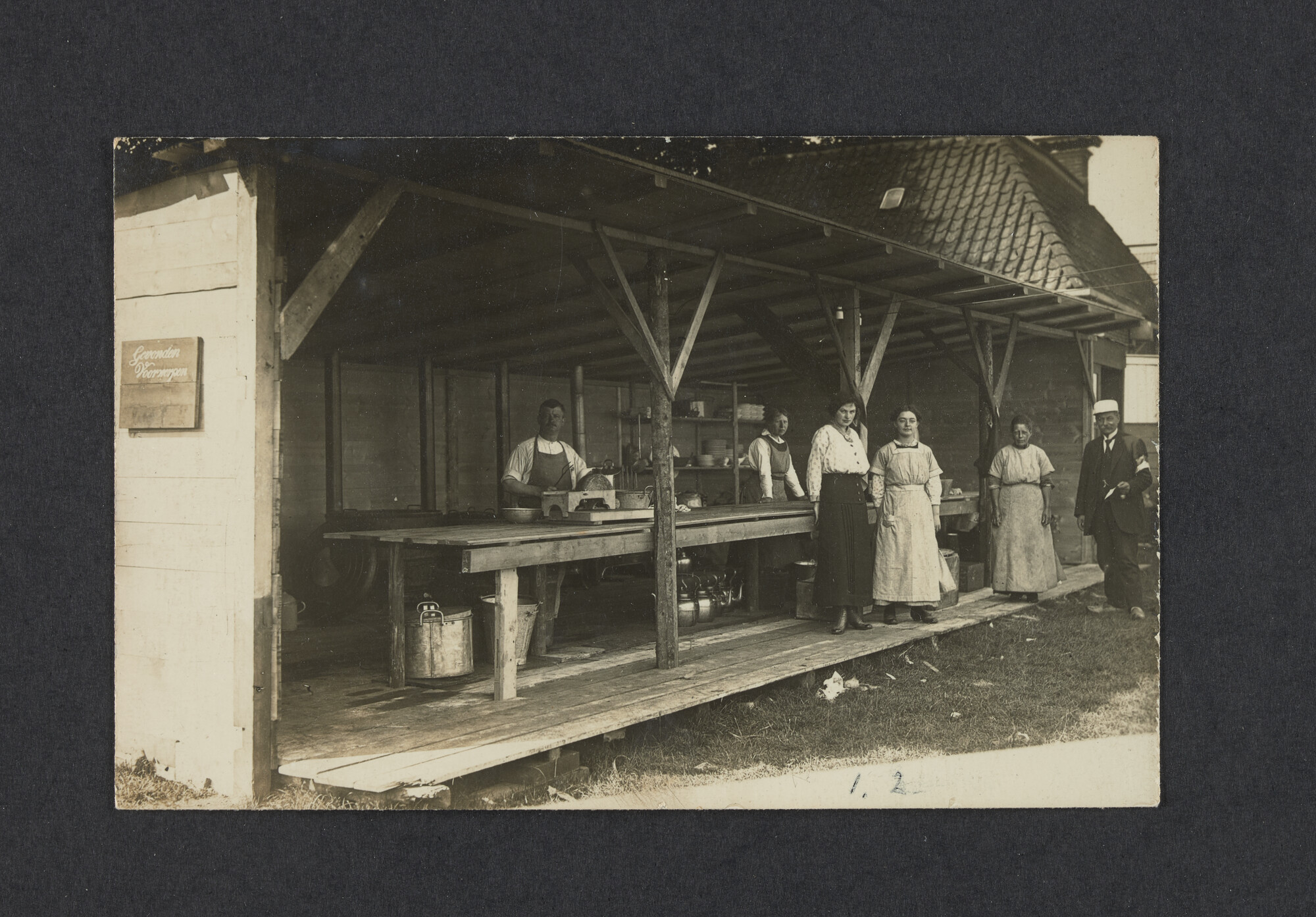 2022.0003; Zwart-wit foto van het keukenpersoneel met leden van het gezin Mink tijdens het eerste waterkamp voor jongens in Langweer (De Friese Meren) in 1915; foto