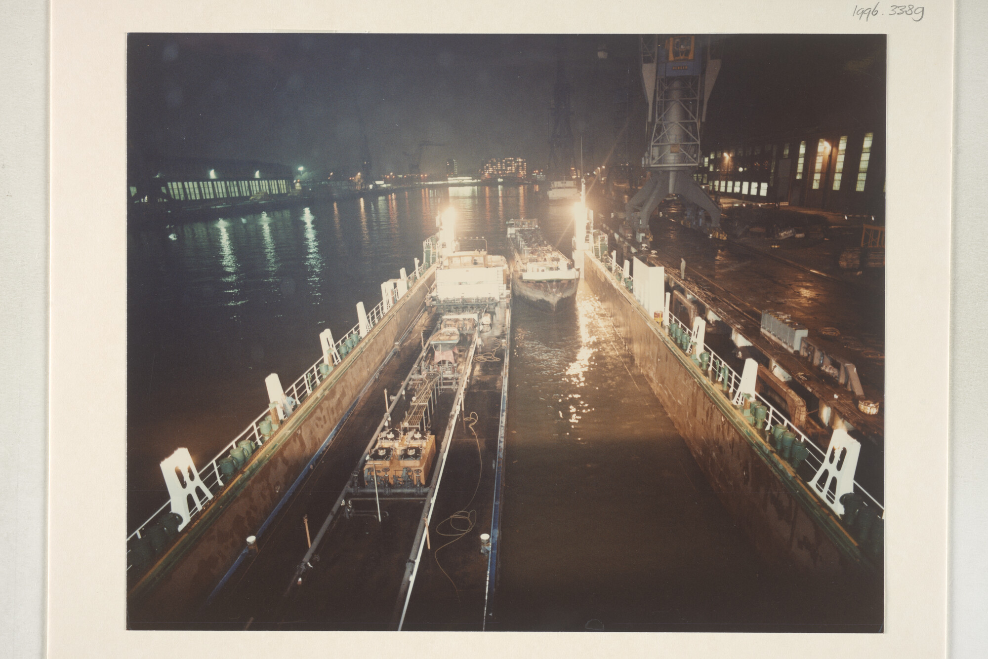 1996.3389; Avondopnames van het klaarmaken voor transport met een dokschip van de binnenvaarttankers ms. 'Leonidas VII' van Leonidas Tankvaart BV; fotoreportage