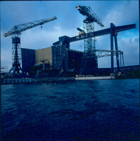 S.9100(3096); Dia (sfeerfoto) NDSM, 150-tons portaal-kraan met in aanbouw zijnde 'Melania'; diapositief