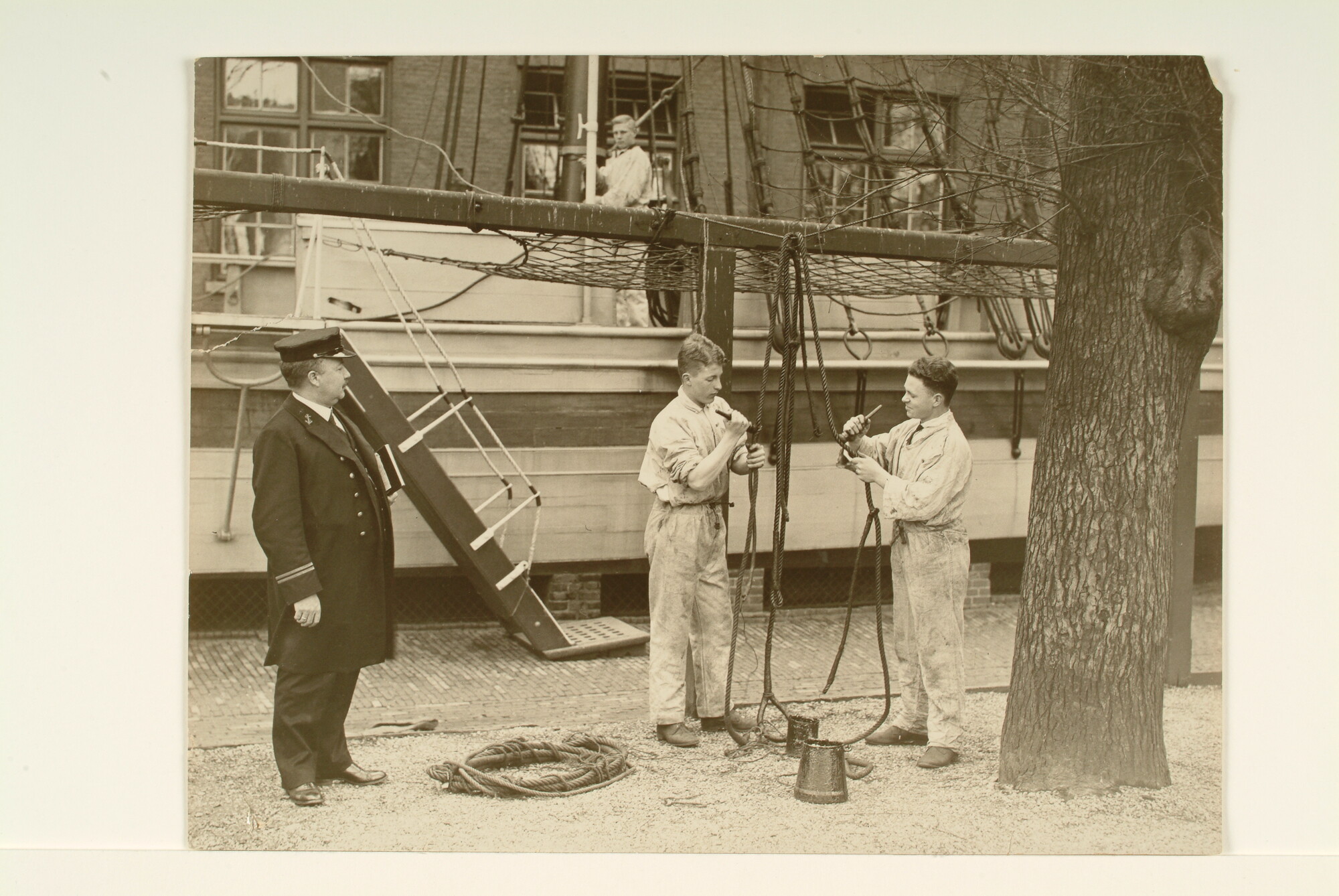 S.7143(1353); Twee leerlingen, onder begeleiding van een bootsman, bezig met het teren van touw; foto