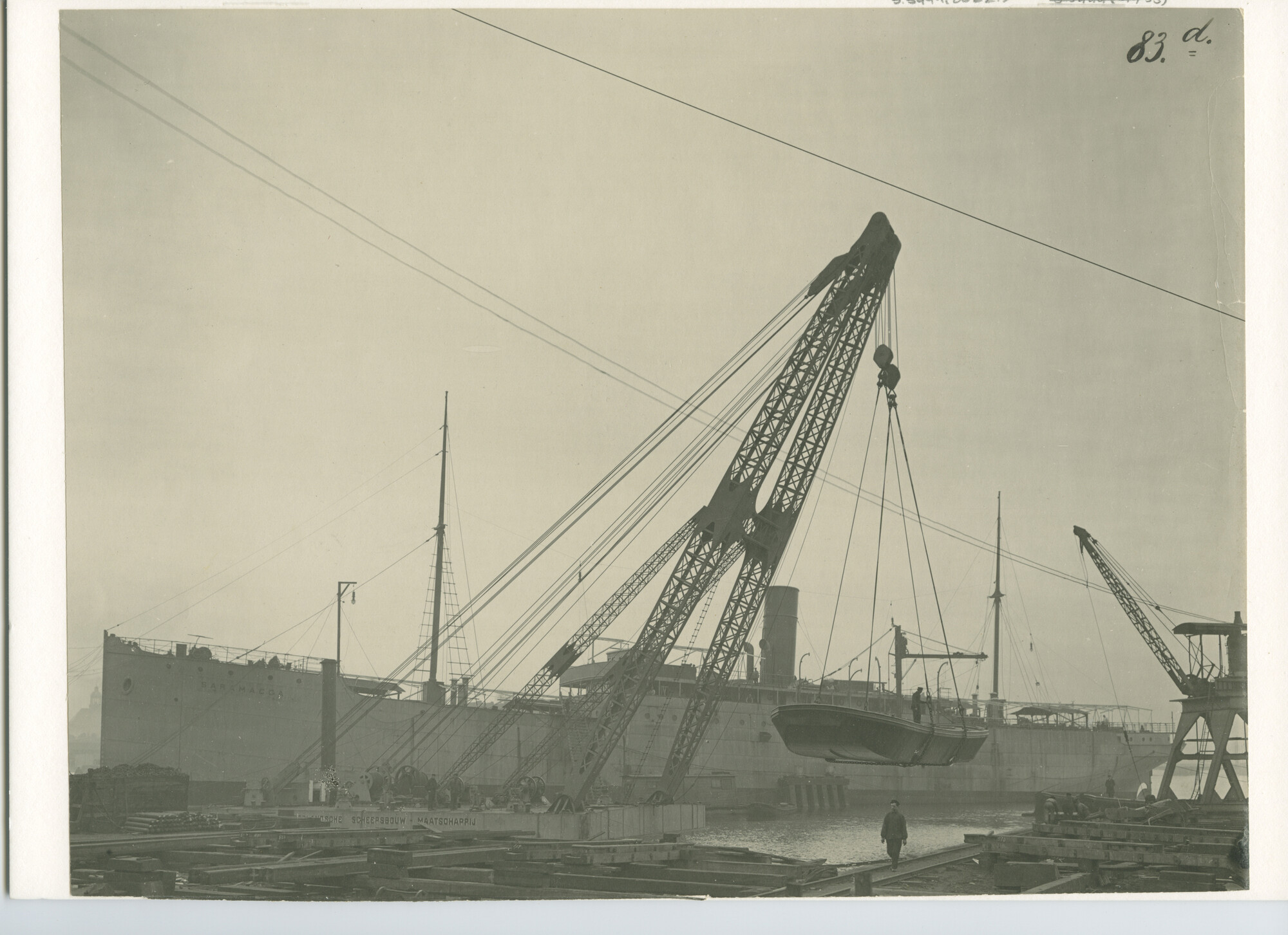 S.5444(00221); Stalen dekschuit in de takels van de drijvende-bok van de NSM, Amsterdam; foto