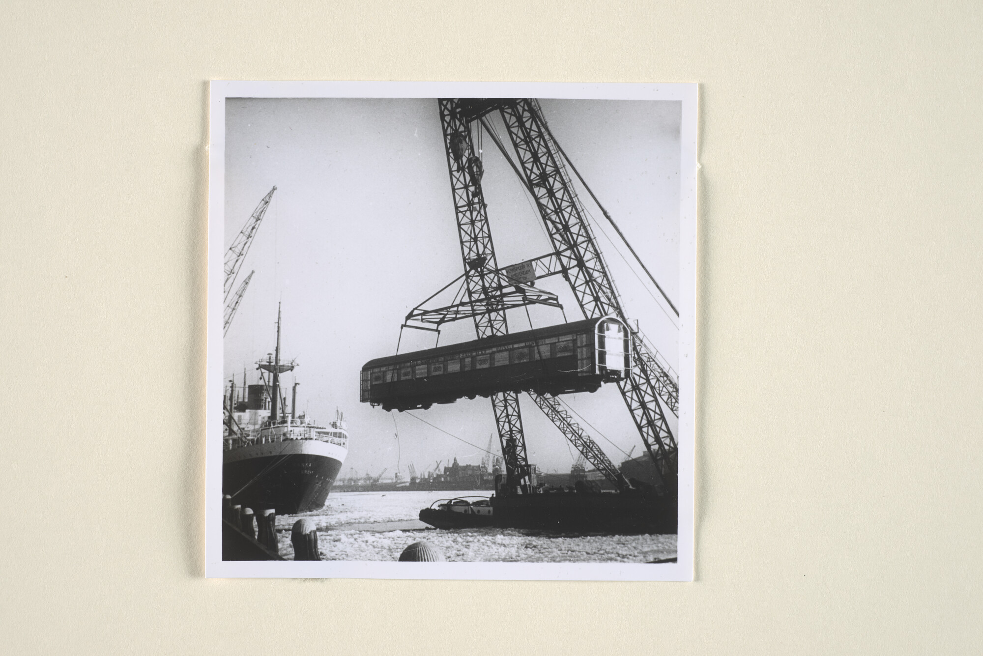 1995.1750; Een drijvende bok van Werkspoor met een spoorwegwagon in de takels manoeuvreert door de bevroren haven van Amsterdam; foto
