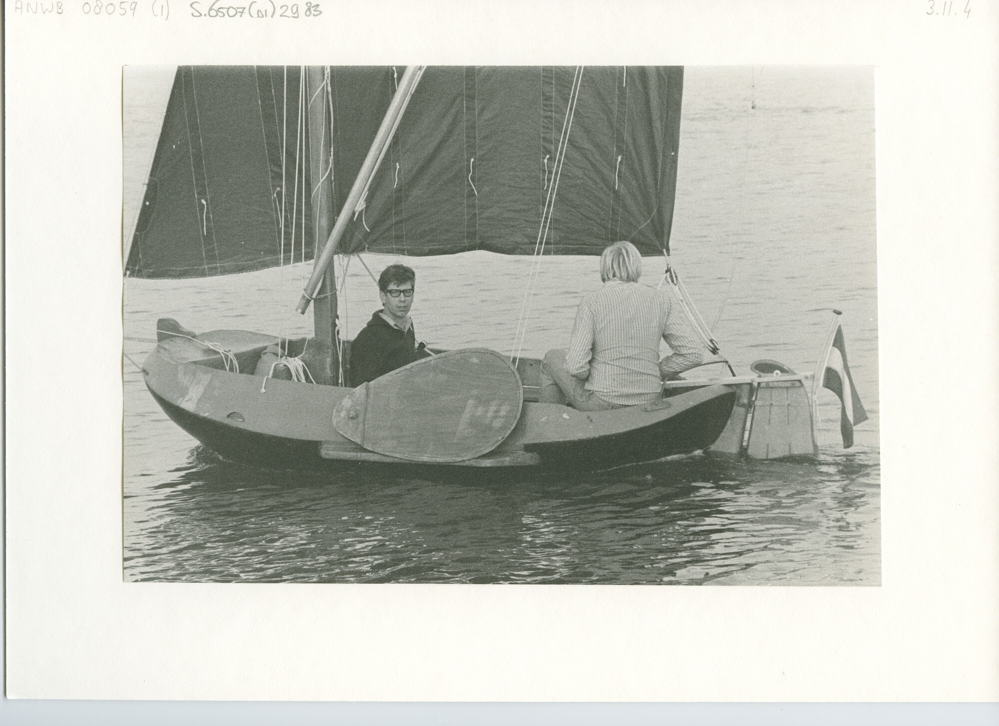 S.6507(01)2983; Bakboords aanzicht van een kunsstof tjotter onder zeil met twee bemanningsleden; foto