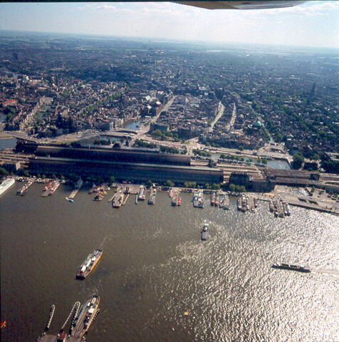 S.9100(7185); Havengezicht te Amsterdam met het IJ. Luchtfoto. Dia (tegenlichtopname) van het Centraal Station met de Ruyterkade; diapositief