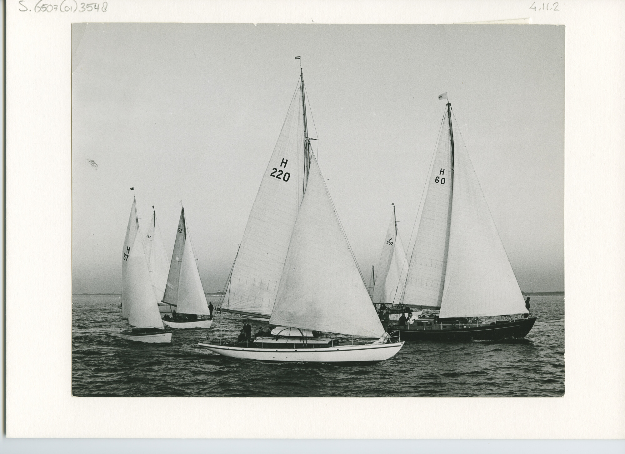 S.6507(01)3548; Zeegaande kajuitzeiljachten in een zeilrace op zee met de kust op de achtergrond; foto