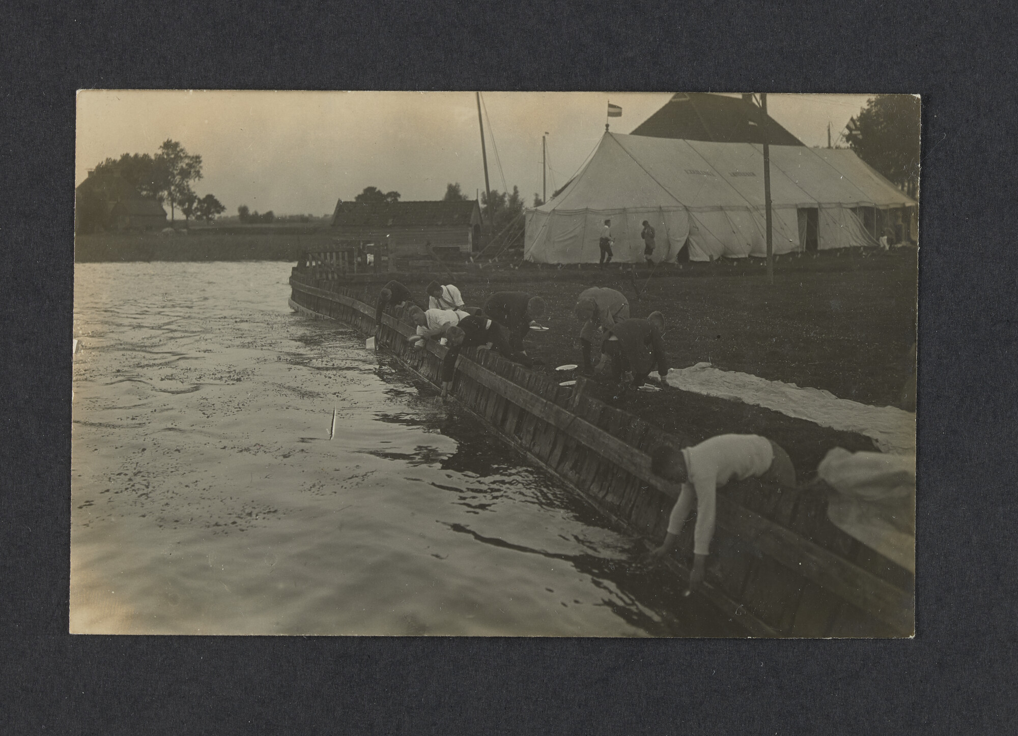 2022.0010; Zwart-wit foto van jongens die de afwas doen in het meer tijdens het eerste waterkamp voor jongens in Langweer (De Friese Meren) in 1915; foto