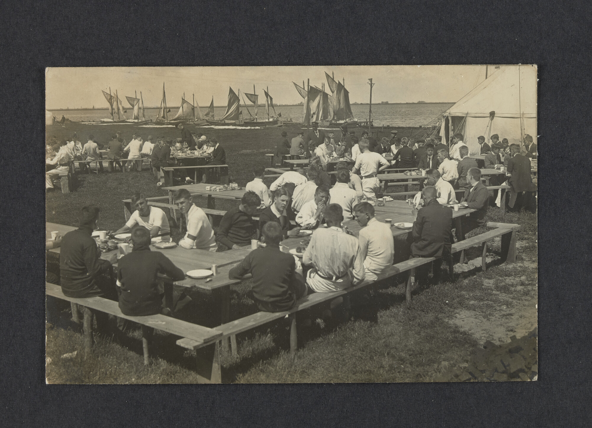 2022.0009; Zwart-wit foto van een openlucht maaltijd tijdens het eerste waterkamp voor jongens in Langweer (De Friese Meren) in 1915; foto