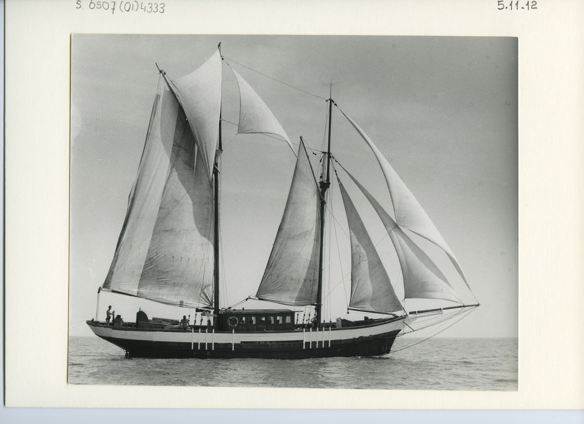 S.6507(01)4333; Een houten gaffelschoener met zwarte romp zeilend met ruime wind op zee; foto