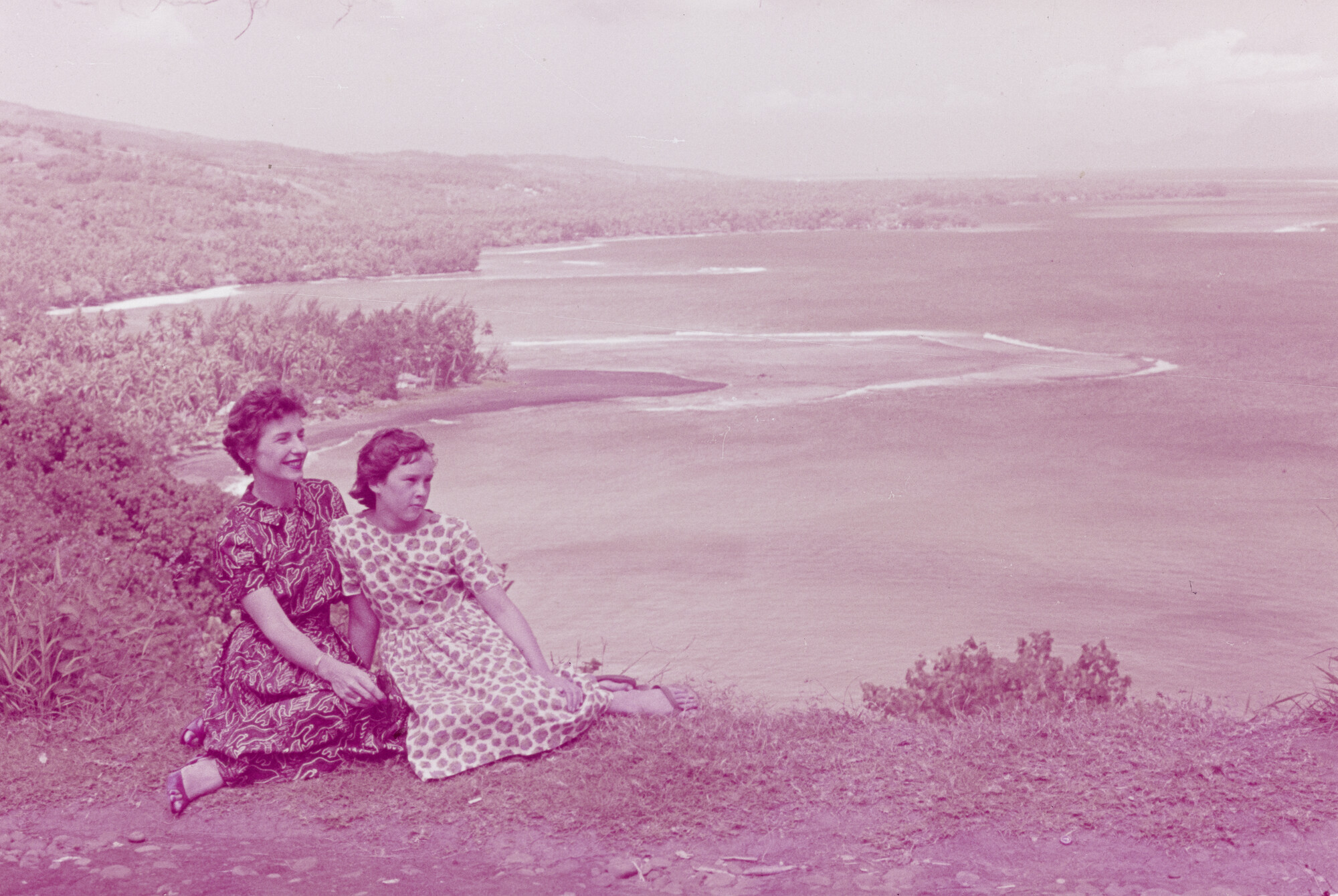 2015.0585; Dia van twee vrouwen die op een hoger gelegen punt uitkijken op de Stille Oceaan op Tahiti; diapositief