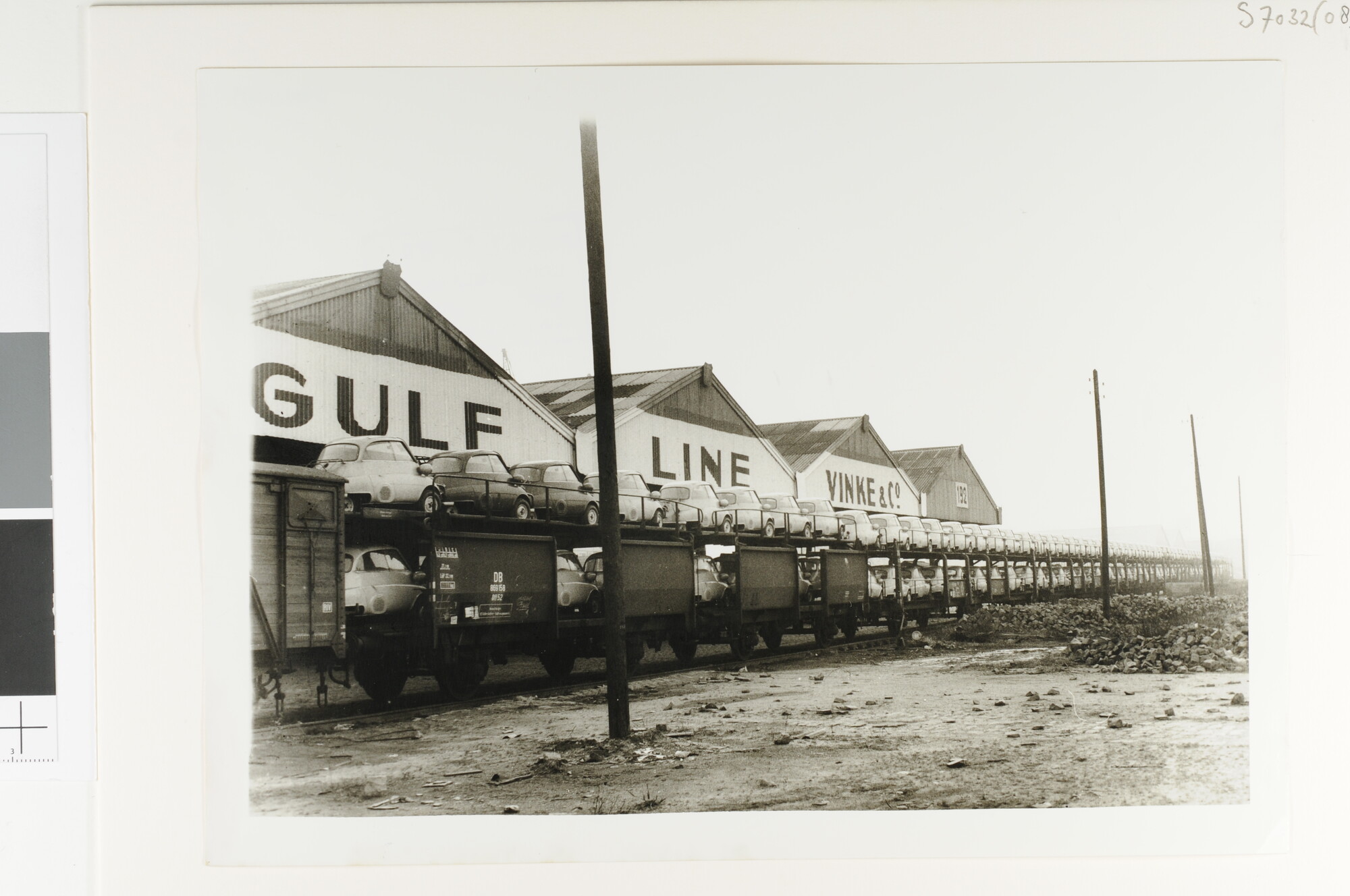 S.7032(089); Een autotrein met nieuwe autos (driewielers) staat afgerangeerd bij een [...]; foto