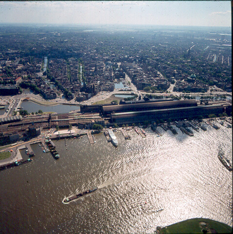 S.9100(7184); Havengezicht te Amsterdam met het IJ. Luchtfoto. Dia (tegenlichtopname) van het IJ en Centraal Station; diapositief