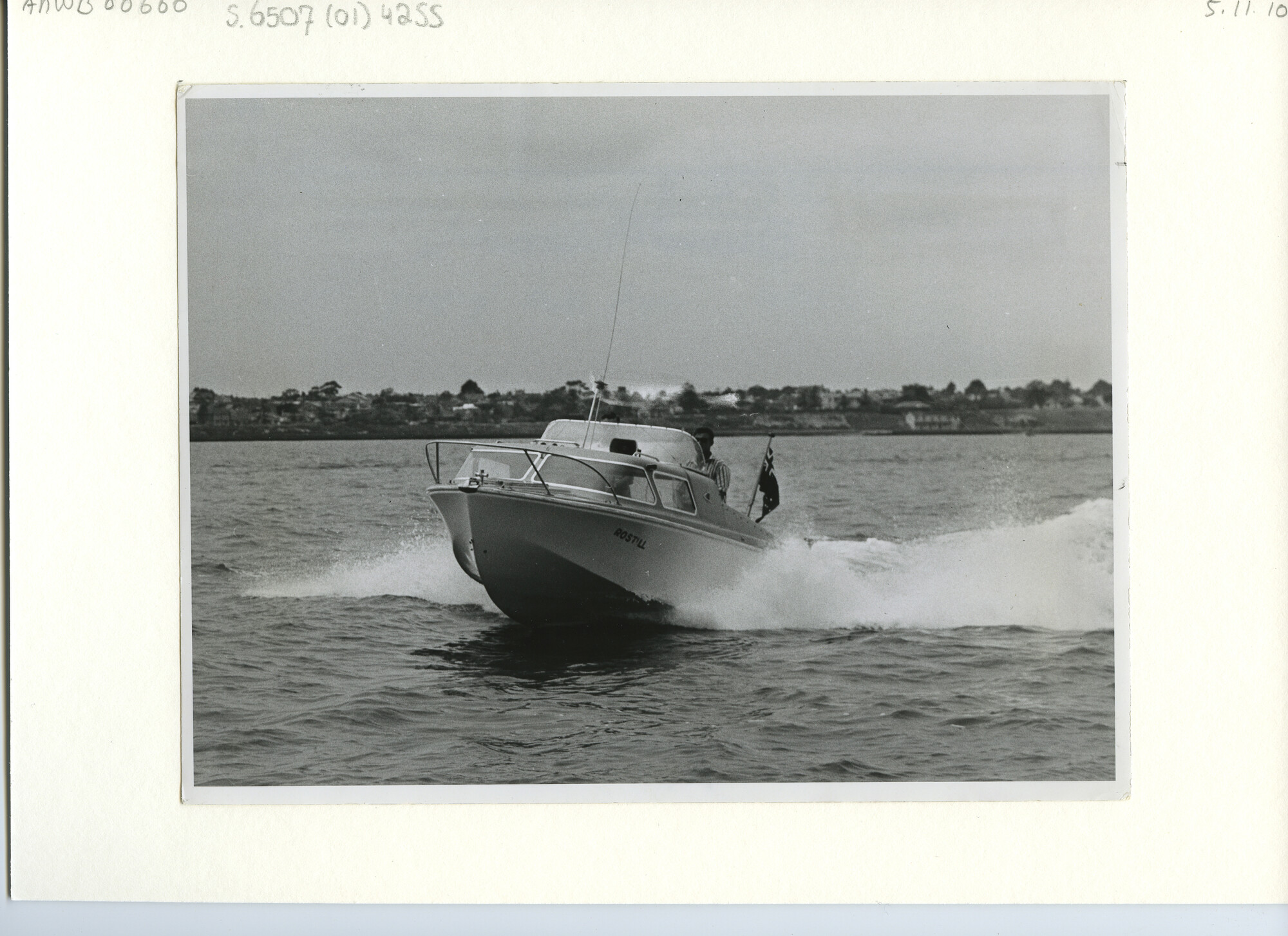 S.6507(01)4255; De Australische speedboat Rostill varend op open water met de kust op de achtergrond; foto