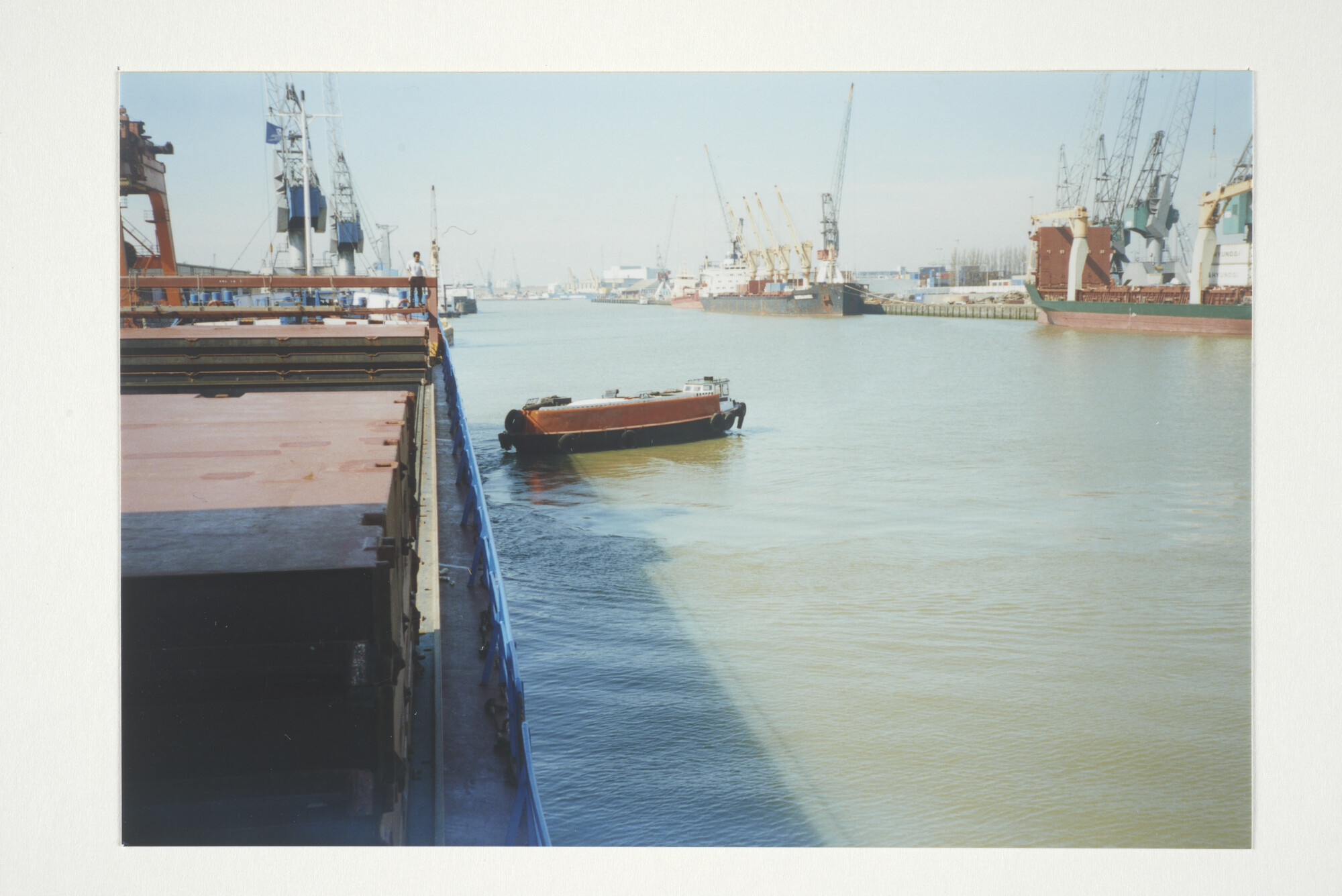 2001.1643; 'Kleinschaligheid in een wereldhaven.' Kleurenfoto van de parlevinker 'Leo' varende langs de coaster ms. 'Rhine Trader' in de Waalhaven [...]; fotoreportage