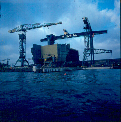 S.9100(3093); Dia (sfeerfoto) NDSM, 150-tons portaal-kraan met in aanbouw zijnde 'Melania'; diapositief