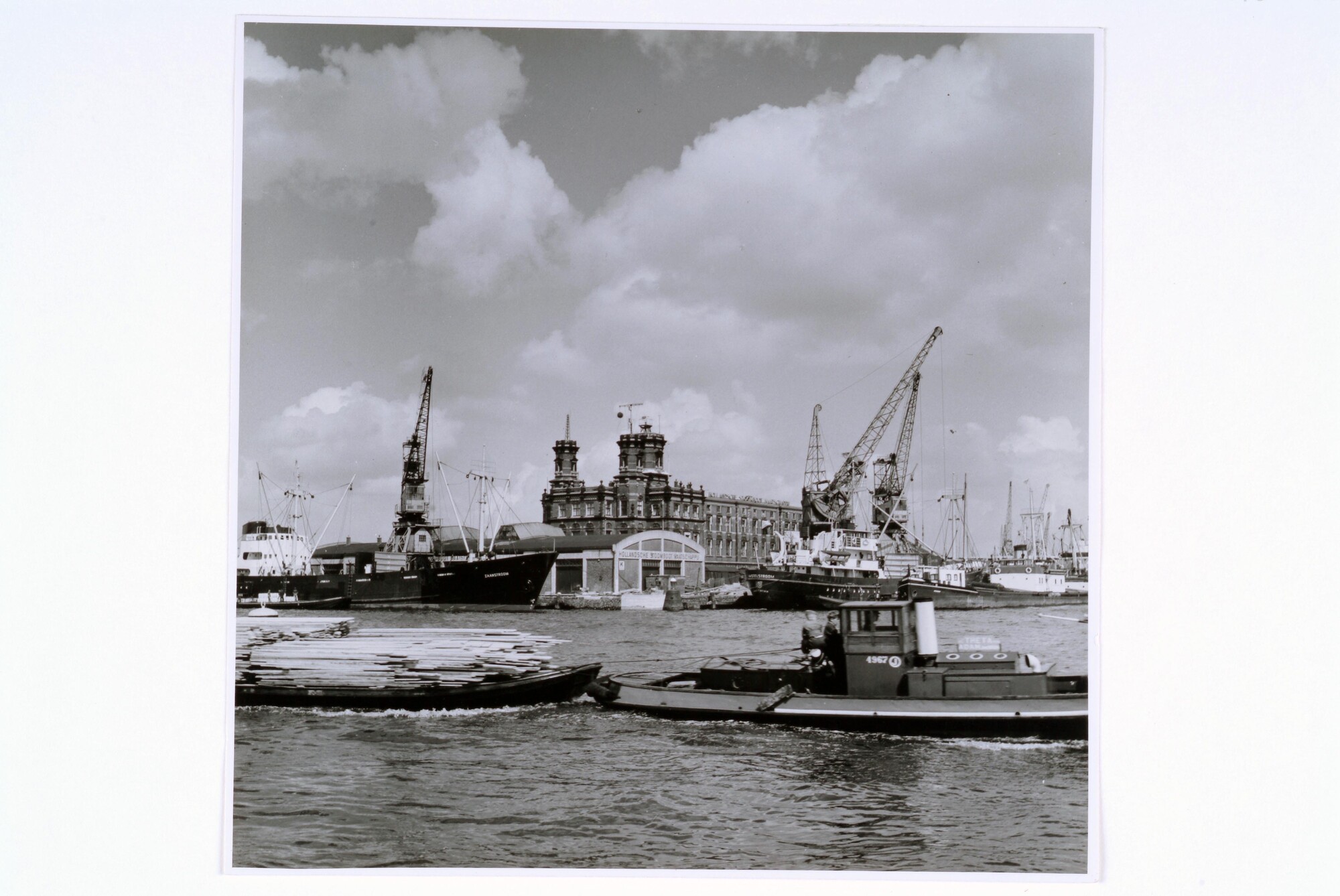 1998.0103; Gezicht op de kop van de Handelskade bij het KNMI-gebouw en de loodsen van de Hollandsche Stoomboot Maatschappij, 1955; foto