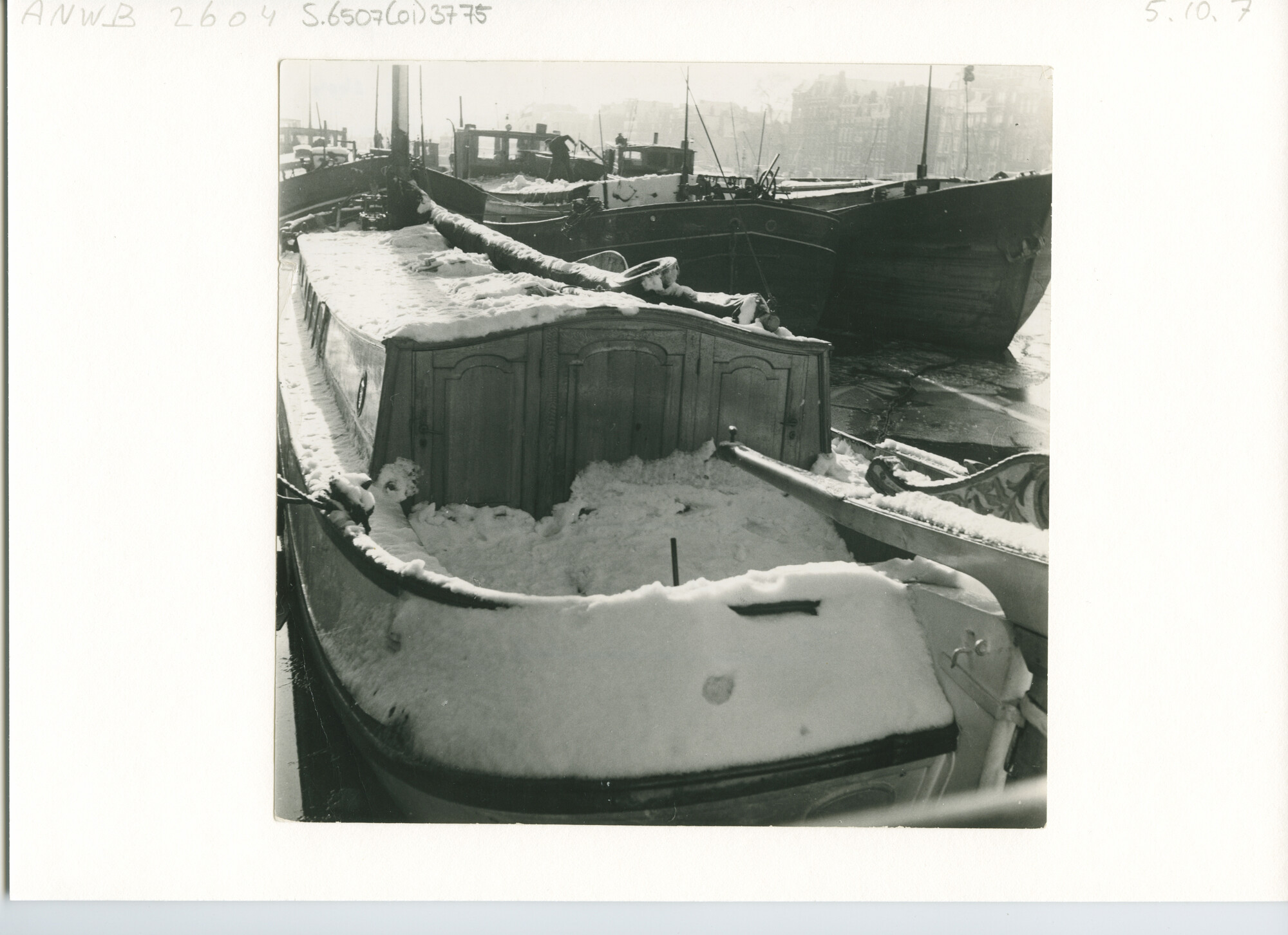 S.6507(01)3775; Binnenvaartschepen en een rond- of platbodemjacht naast elkaar onder een vracht sneeuw afgemeerd in bevroren water; foto
