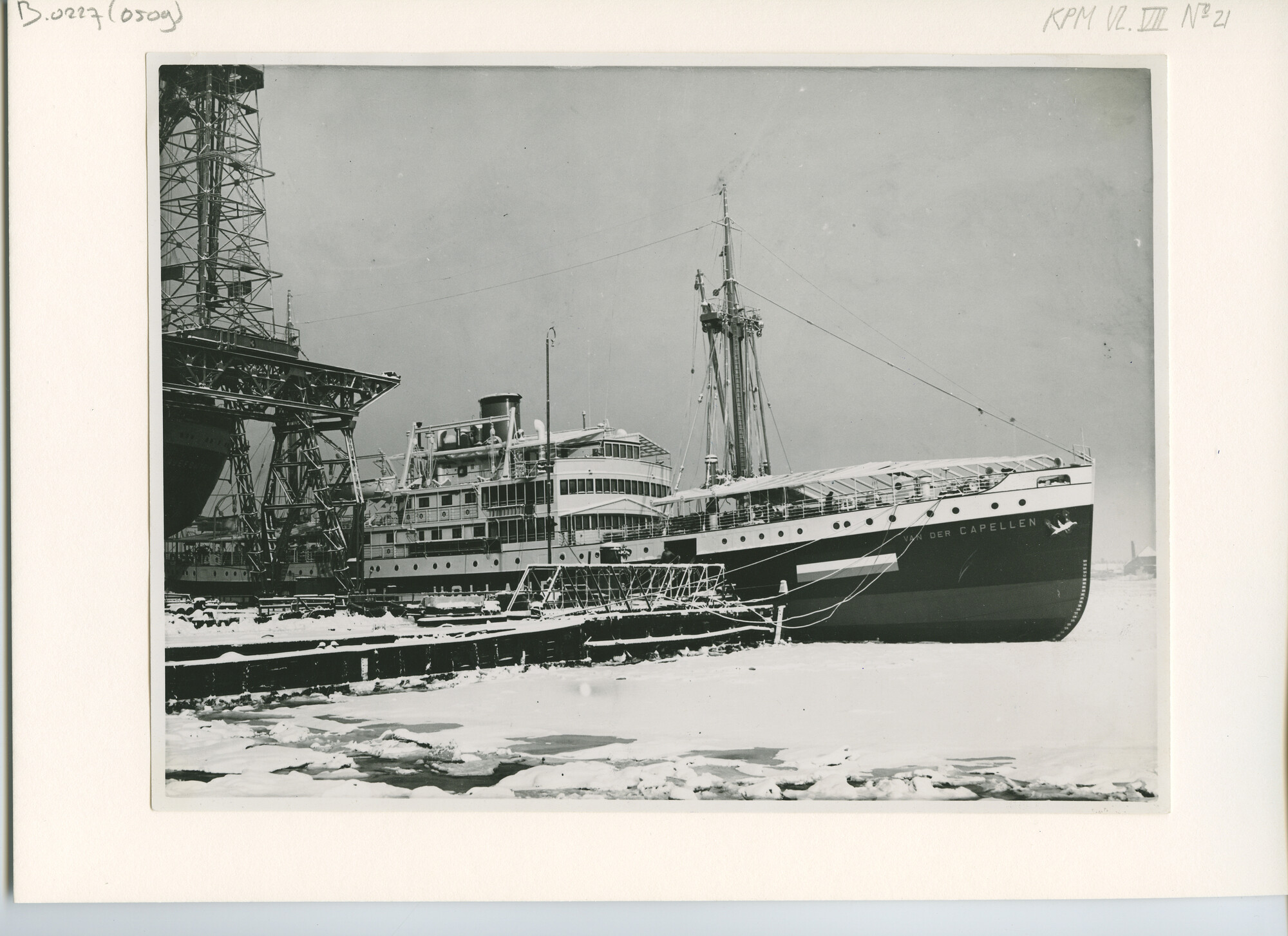 B.0227(0509); Foto van ms. Van der Capellen van de KPM vast in het ijs aan de afbouwkade van de scheepswerf en Machinefabriek van P. Smit jr; foto