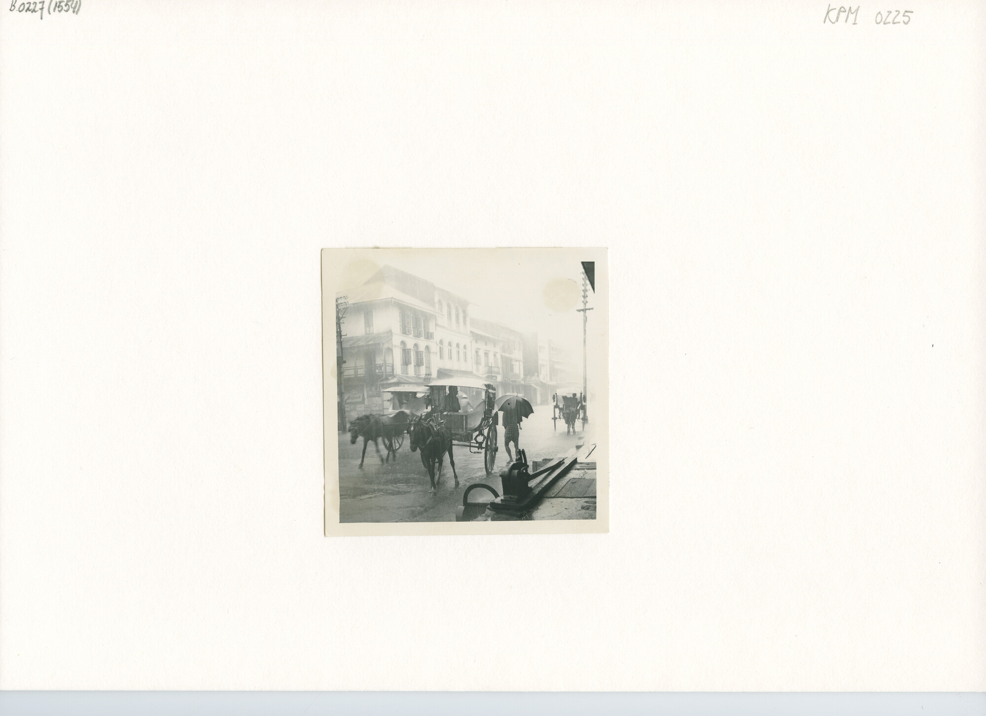 B.0227(1554); Straatgezicht. Passagieren te Moulmein (Burma) in de moesson-regen; foto