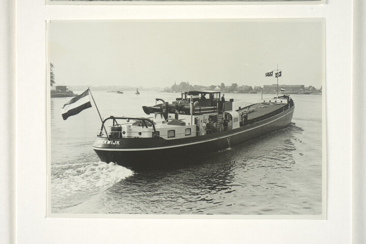 S.5219(12)0705; Foto's van het vrachtschip ms. Roekwijk van de Nieuwe Rijnvaart Maatschappij op een rivier en aan een kade; fotoreportage