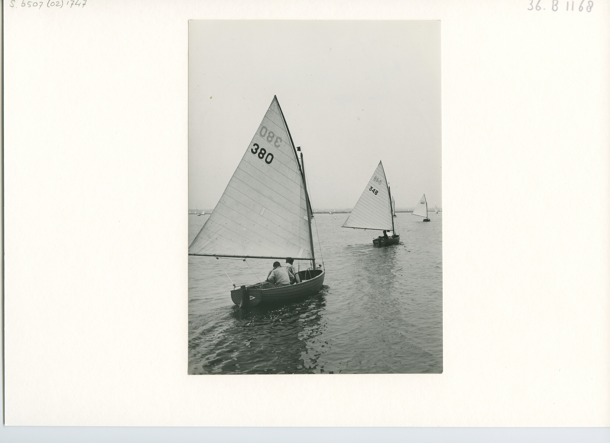 S.6507(02)1747; Zwart-wit foto van twaalfvoets-jollen in een ruimwinds rak op de Mooie Nel bij Haarlem tijdens een wedstrijd van de Haarlemse Jacht Club, 1952; foto