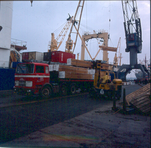 S.9100(8362); Dia van gezaagd hardhout en containers worden geladen op het Brazaliaanse vrachtschip ms. 'Copacabana'; diapositief