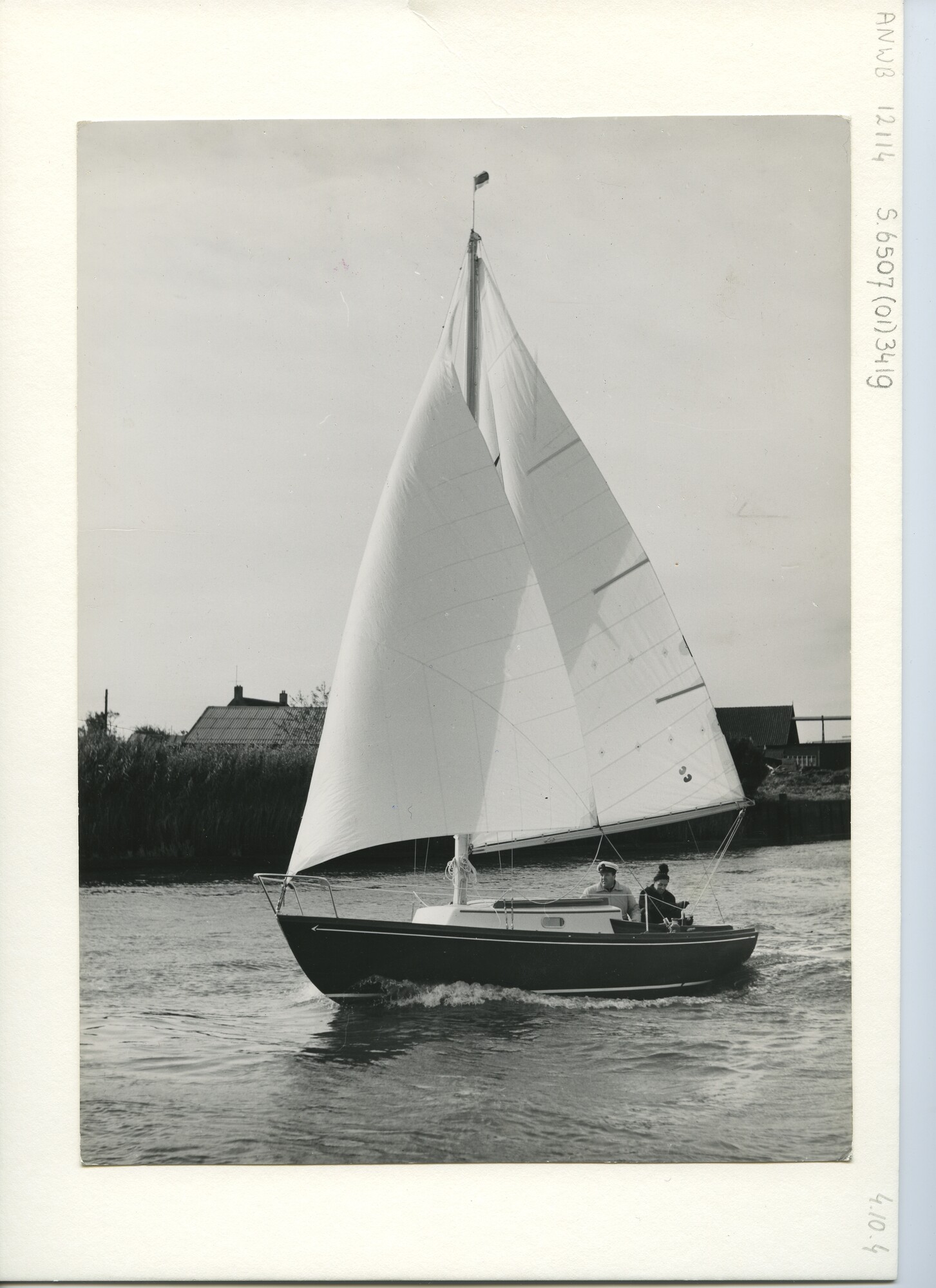 S.6507(01)3419; Een donker polyester kajuitzeiljacht met witte opbouw zeilend onder grootzeil en fok; foto