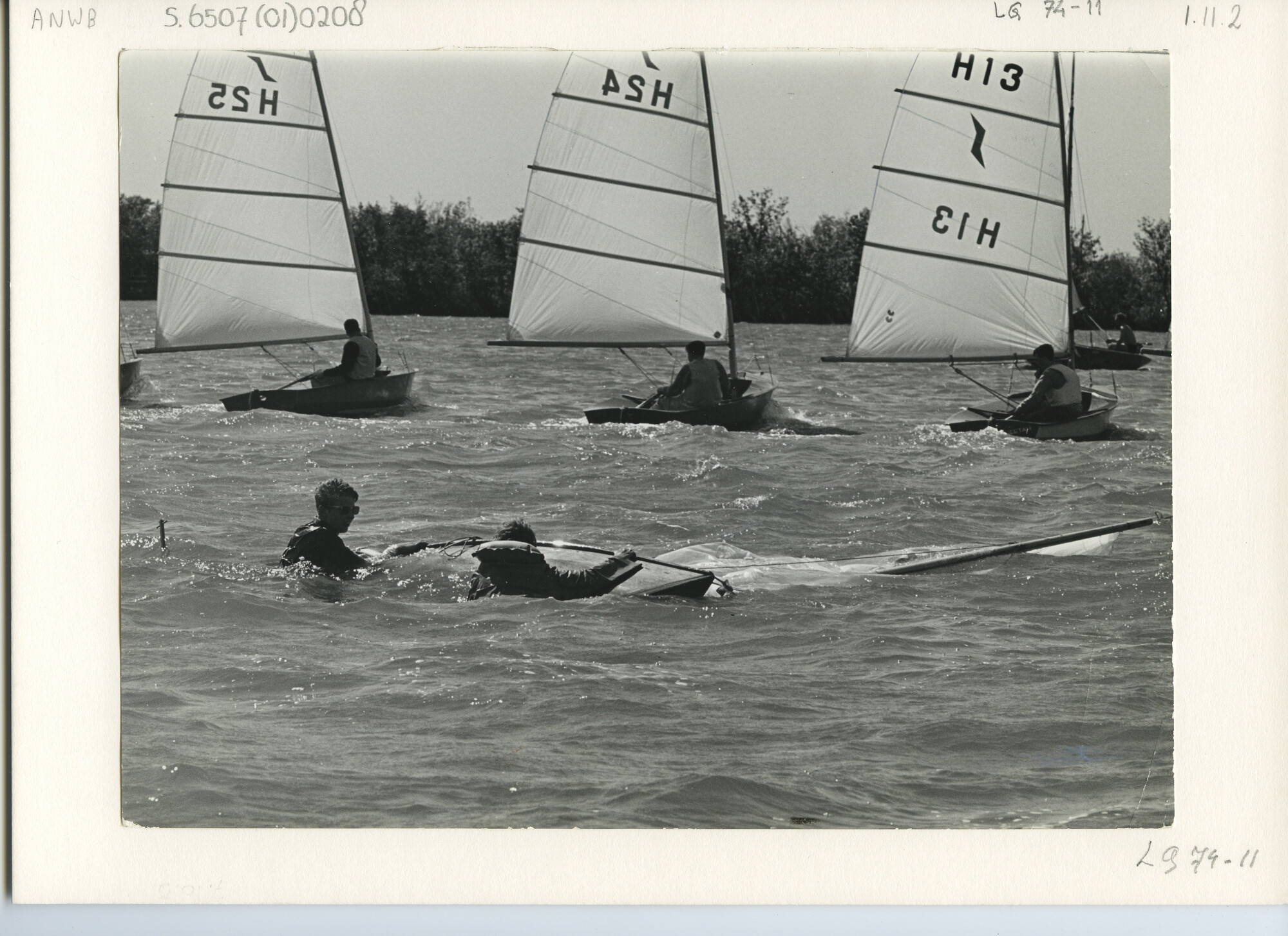 S.6507(01)0208; Goudse Zeilweek 1963: de Soloklasse passeert voor de wind een omgeslagen tweemansboot; foto