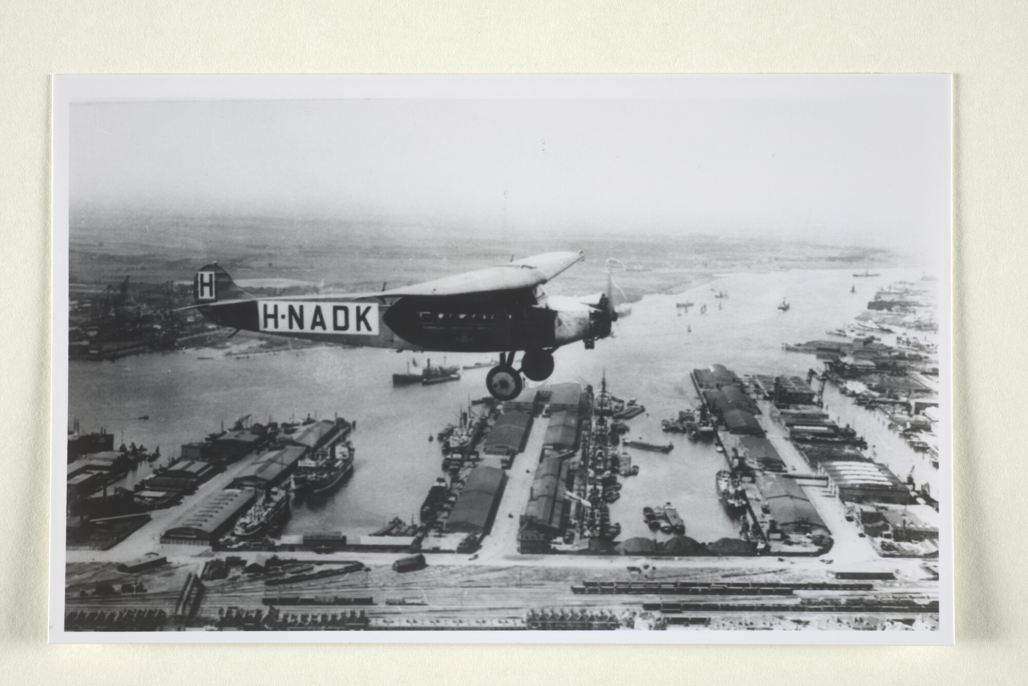 1997.1153; De Fokker H-ANDK van de KLM gezien boven de Lek- en IJselhaven in Rotterdam, omstreeks 1928; foto