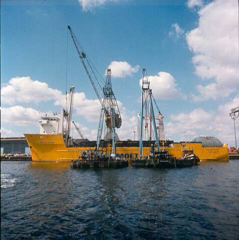 S.9100(6896); Dia van het zwaarladingschip 'Happy Rider' ladende met twee bokken een offshore ponton; diapositief